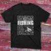 Black T-shirt with the word "Fishing" repeated four times in white text across four lines, with a Betta fish image over some of the words, shown against a light blue background.