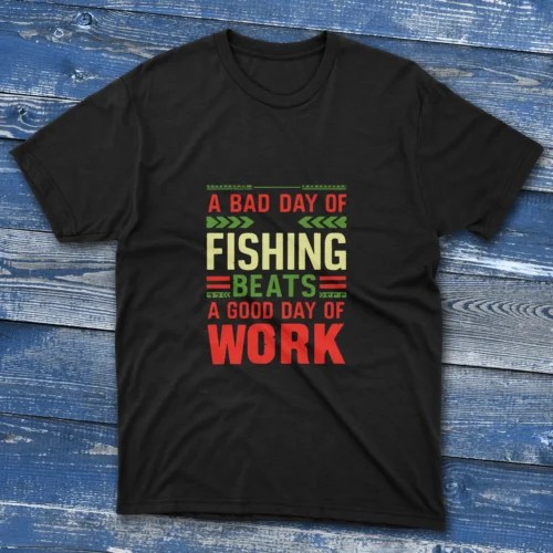 Black T-shirt with bold colorful text saying "A bad day of fishing beats a good day of work," shown on a light blue wooden background.