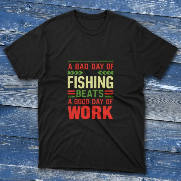 Black T-shirt with bold colorful text saying "A bad day of fishing beats a good day of work," shown on a light blue wooden background.