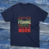 navy T-shirt with bold colorful text saying "A bad day of fishing beats a good day of work," shown on a light blue wooden background.