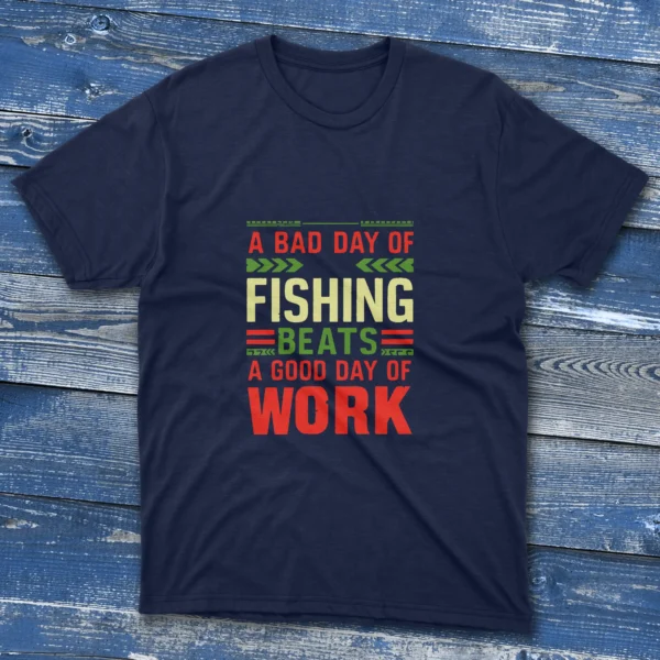 navy T-shirt with bold colorful text saying "A bad day of fishing beats a good day of work," shown on a light blue wooden background.